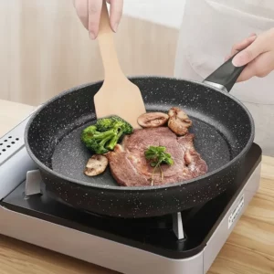 Steak et champignons dans la poêle noire antiadhésive sur une plaque de cuisson